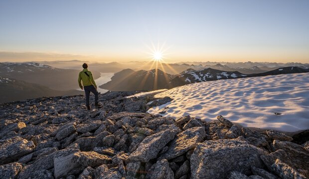 Hiker looking into the sunset, sun star, view of mountains and fjord Faleidfjorden, top of Sk&aring;la, Loen, Norway