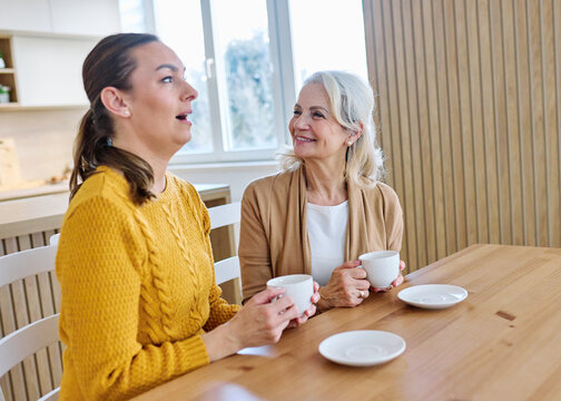 Portrait of mother and daughter  having fun, chating drinking coffee, sitting and hugging  at home, family life, parenting, love and bonding concepts