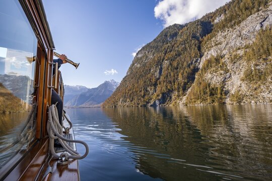 A trumpet is played on the echo wall of a tourist boat, K&ouml;nigssee, autumnal mountain landscape reflected in the lake, Berchtesgaden National Park, Berchtesgadener Land, Upper Bavaria, Bavaria, Germany