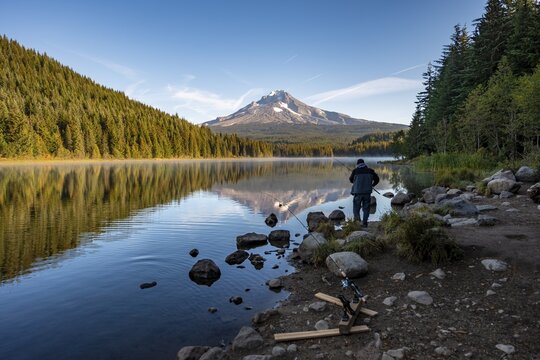 Anglers on the lake shore, reflection of Mt. Hood volcano in Trillium Lake, in the morning light, Oregon, USA