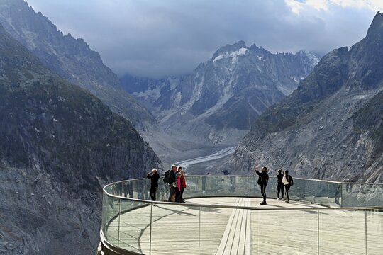 A group of people take pictures of themselves on the viewing platform in front of the Mer de Glace glacier, Mont-Blanc, Chamonix-Mont-Blanc, Haute-Savoie, France