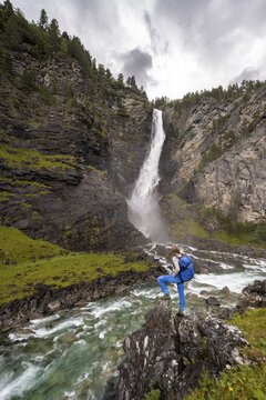 Hiker standing on rocks by river Driva, Sv&oslash;ufallet waterfall, &Aring;motan gorge, Gj&oslash;ra, Norway