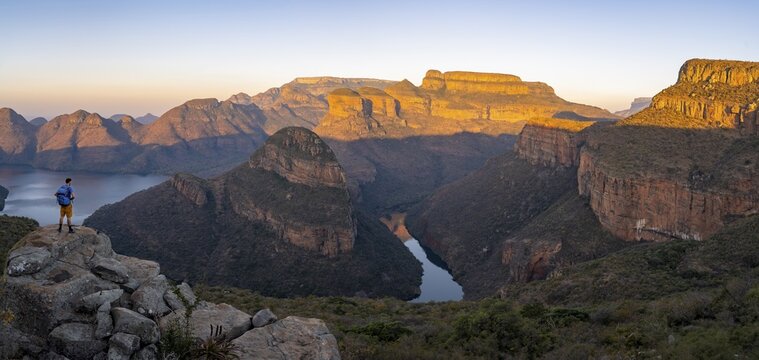 Tourist enjoying the view from a rock, Panorama, Sunset at Blyde River Canyon with Three Rondawels peak, View of canyon with Blyde River and Table Mountains in the evening light, Canyon landscape, Panorama Route, Mpumalanga, South Africa
