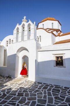 Young woman with red dress in walks into an aisle, Agios Antonios, Greek Orthodox Church, Marpissa, Paros, Cyclades, Greece