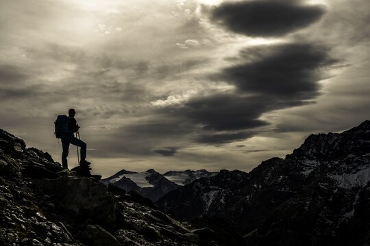 Climbers on rocks in backlight with cloudy sky in the background South Tyrolean mountains, Martell valley, Merano, Vinschgau, South Tyrol, Italy