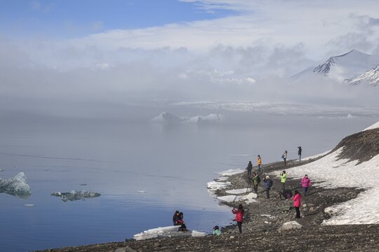 Tourists standing at glacier lagoon, ice floes, glacier, fog, winter, sunny, J&ouml;kulsarlon, Iceland