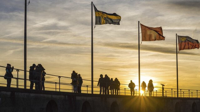 People, silhouettes, flags, harbour in Lindau am Lake Constance, Bavaria, Germany
