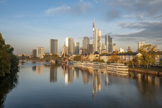 Excursion boats on the river bank, view over the Main, skyline reflected in the river, skyscrapers in the banking district in the morning light, Frankfurt am Main, Hesse, Germany