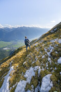 Hiker on hiking trail, Inn valley and mountain panorama in the background, descent from Hohe Munde, Mieminger Kette, Tyrol, Austria