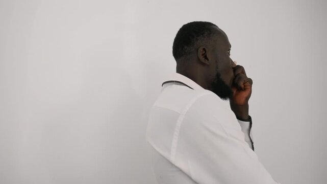 Black man on phone in profile with hand to chin, white shirt and tie, marble counter at side, decisive expression confirming or cancelling date plans, tension mixed with resolve and quiet intensity