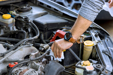Fototapeta premium Man works on car engine in garage to perform maintenance check for issues