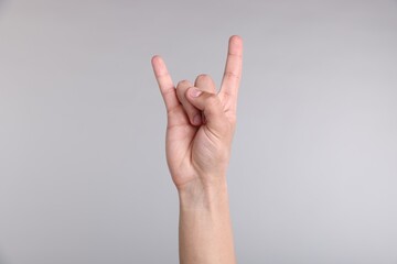 Fototapeta premium Man showing rock gesture on grey background, closeup