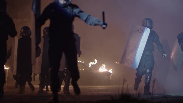 Riot Police with Shields and Batons Charging Through Smoky Street with Fire