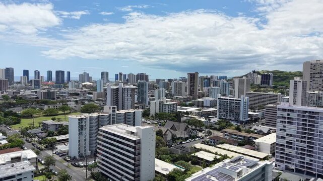 Aerial view rising up above multiple apartments and condos overlooking the greater city of Honolulu and Punchbowl on Oahu, Hawaii.