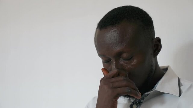 Weary man leaning against wall silently. Office worker appearing drained and overwhelmed with fatigue. Man dressed in business attire shows clear signs of extreme exhaustion and stress