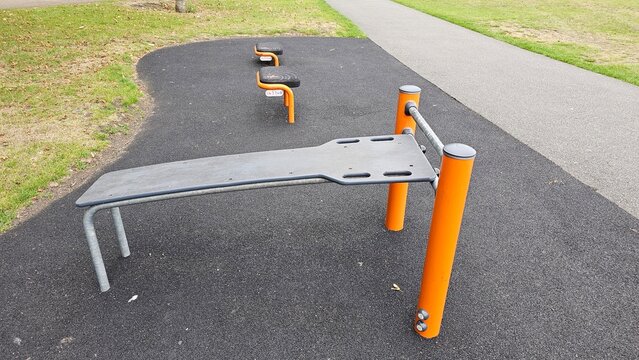 Outdoor fitness equipment including sit-up bench and step platforms in a public park, England, UK