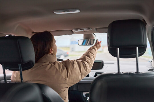 Woman adjusting her rearview mirror inside a car, ensuring clear visibility for safe and focused driving