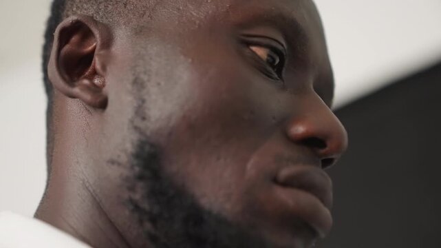 Black man profile closeup showing anticipation before date, side gaze and bearded jawline, quiet nervous energy, sweat sheen under studio light, contemplative pause, cinematic mood