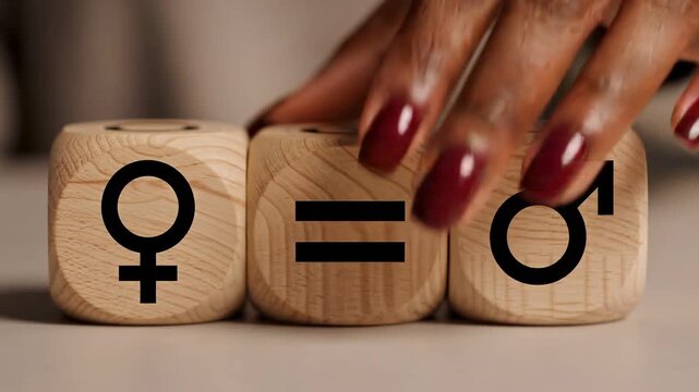 Gender equality concept: hand rotating wooden dice with female and male symbols