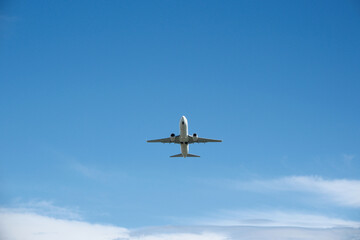Fototapeta premium White Airplane Taking Off Against Blue Sky and Clouds