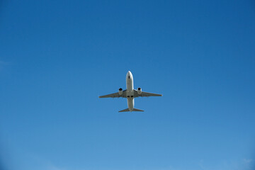 Fototapeta premium White Airplane Taking Off into Clear Blue Sky, Low Angle View