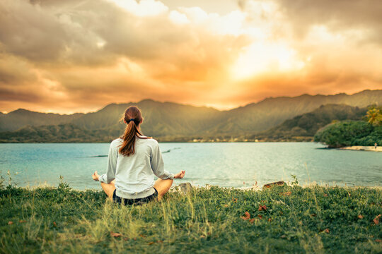 Woman Meditating By Tropical Ocean At Sunset In Hawaii Wellness, Mindfulness, And Inner Peace Concept
