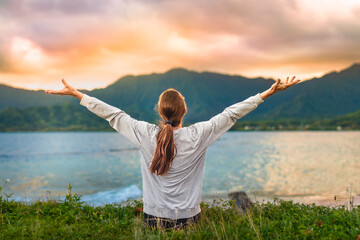 Woman Raising Arms In Freedom By Tropical Ocean And Mountains At Sunset In Hawaii Wellness...