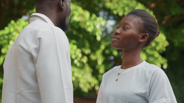Love expressed through caring gestures. Passionate couple embraces under sunny skies. Romantic partners demonstrate their love with gentle caresses beneath glowing sunlight and lush trees