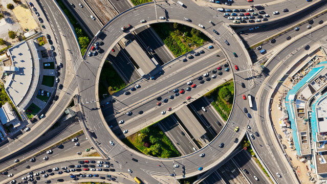 Urban infrastructure featuring a complex highway roundabout with multiple lanes and elevated roads, managing heavy traffic flow and connecting various city destinations during daytime