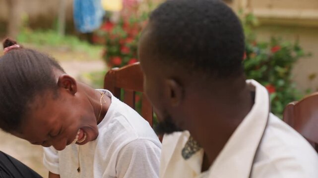 Black couple sharing romantic outdoor date, laughing and leaning close on garden bench, candid conversation with shy smiles, playful teasing, warm sunlight, casual white outfits, genuine chemistry