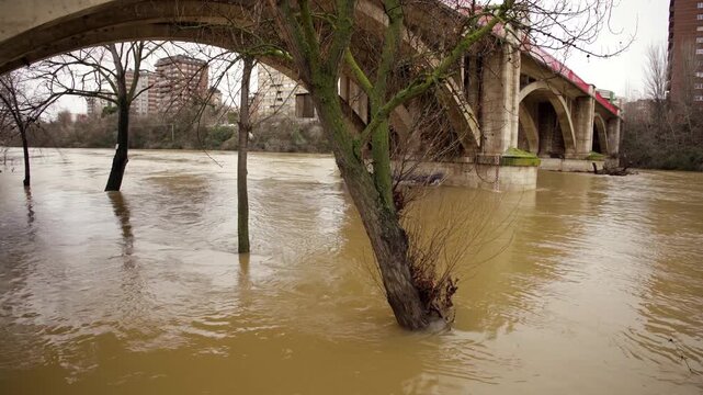 Flooded Pisuerga River flowing under the concrete arch of Garcia Morato Bridge, Spain.
