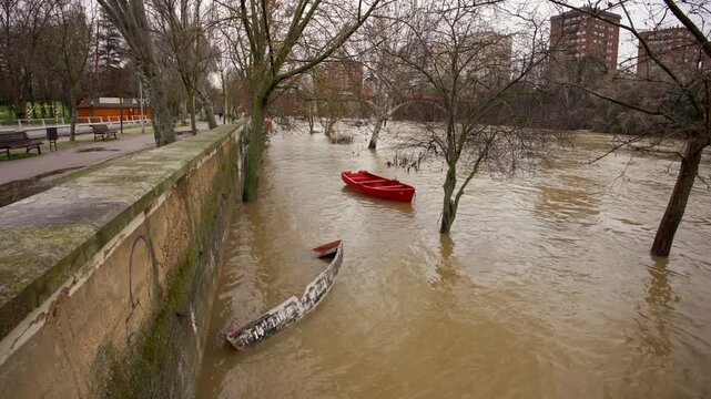 Flooded Pisuerga River overflowing pedestrian walkway in Valladolid, Spain.