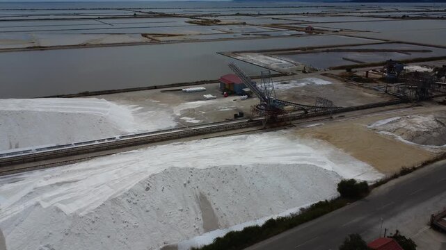 Aerial establishing shot of industrial stacker crane and salt heaps