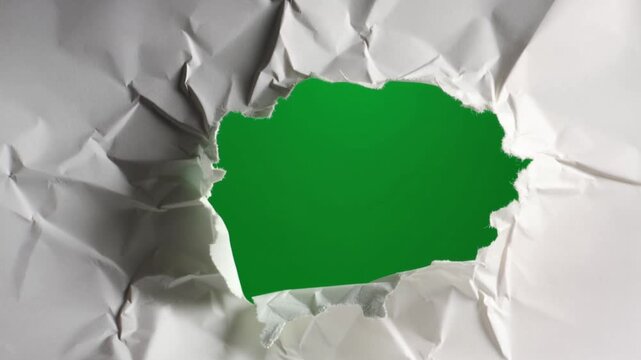 A green shape emerges from a torn crumpled paper background texture