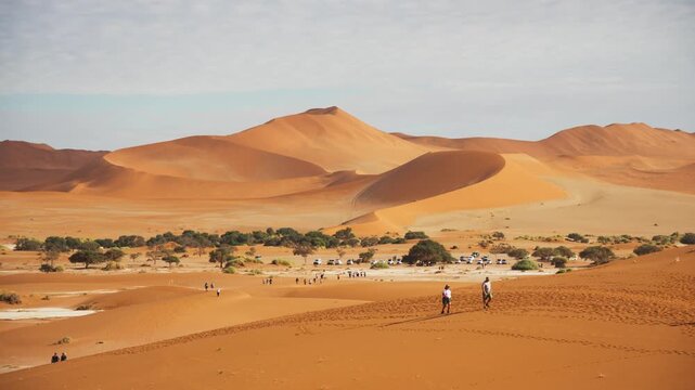 Tourists climbing impressive sand dunes of Sossusvlei and Dead Vlei in Namib Naukluft National Park, iconic travel destination in the heart of Namibia
