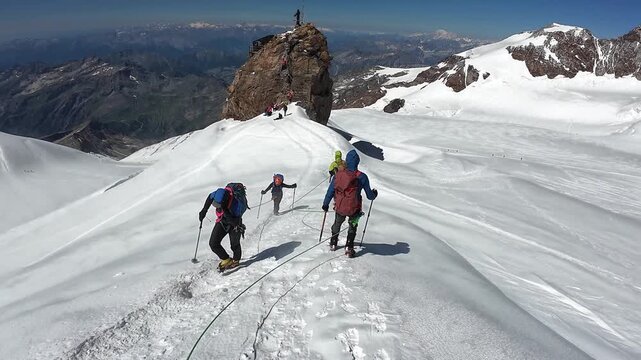 POV mountaineering in rope team with mountaineers towards summit Balmenhorn and mountain glacier panorama with Gran Paradiso in summer in Pennine Alps, Italy