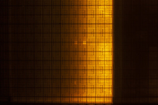 Aerial view of a large greenhouse complex glowing with orange light at night, highlighting the geometric grid of the glass structures.
