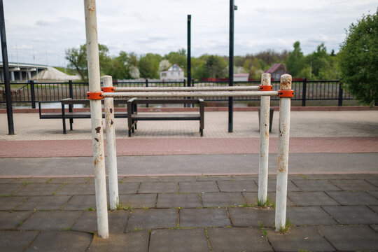Close-up of metal parallel bars with orange clamps in an outdoor sports ground.