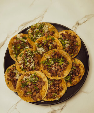 Beef in a tortilla with cilantro and onion scattered on a black plate