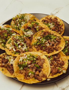 Beef in a tortilla with cilantro and onion scattered on a black plate