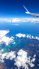 Fototapeta premium Aerial view of ocean and land with clouds and airplane wing