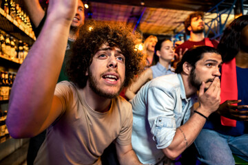Naklejka premium Friends celebrating exciting football moment in sports pub