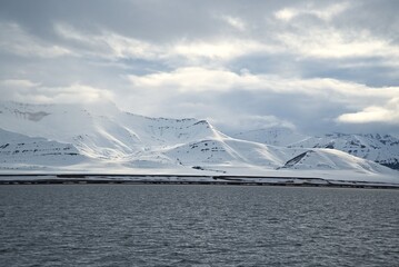 Snow covered arctic mountains at the edge of the fjord © rene_dra