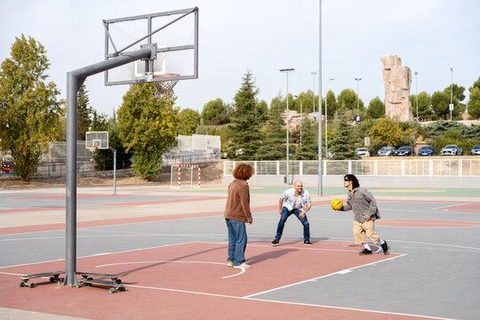 Urban skater friends playing basketball on outdoor court
