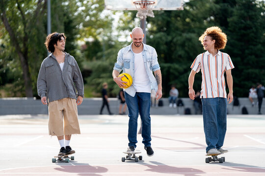 Friends skate together in urban court on sunny afternoon