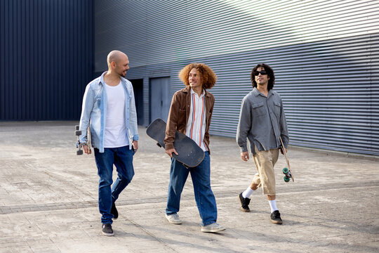 Urban skater friends walking together with skateboards