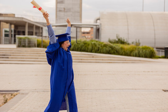 Female graduate student celebrating outdoors with diploma