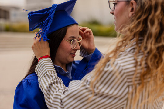 Female student in blue cap and gown at graduation moment