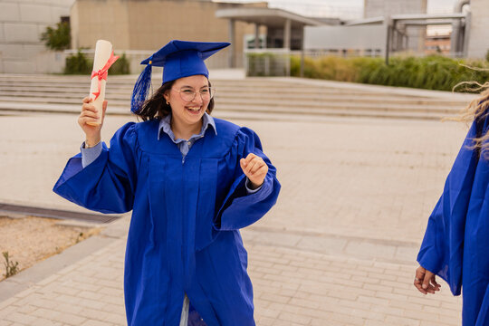 Happy female student celebrating graduation with diploma