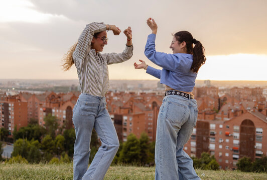 Friends dancing at sunset viewpoint in Madrid cityscape